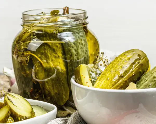 Vaso di cetriolini in agrodolce, con alcuni in una ciotola. Perfetti per un antipasto croccante e saporito.