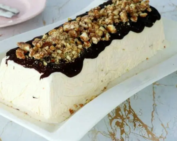 Un delizioso parfait di mandorle, ricoperto di cioccolato fuso e granella croccante, pronto per essere gustato.