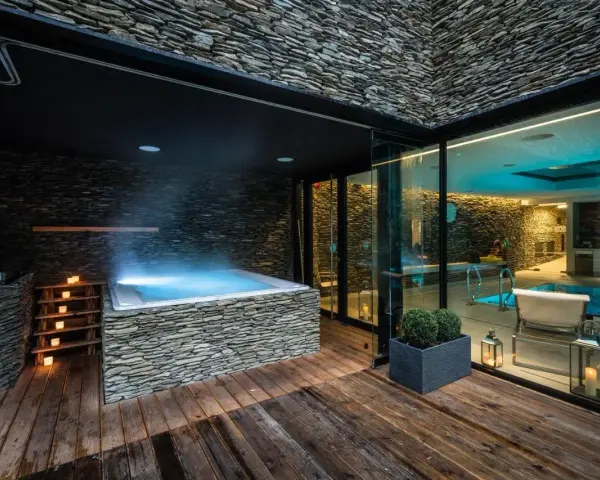 Relaks w nowoczesnym spa na Dolnym Śląsku: jacuzzi z kamienną obudową, basen i nastrojowe oświetlenie.