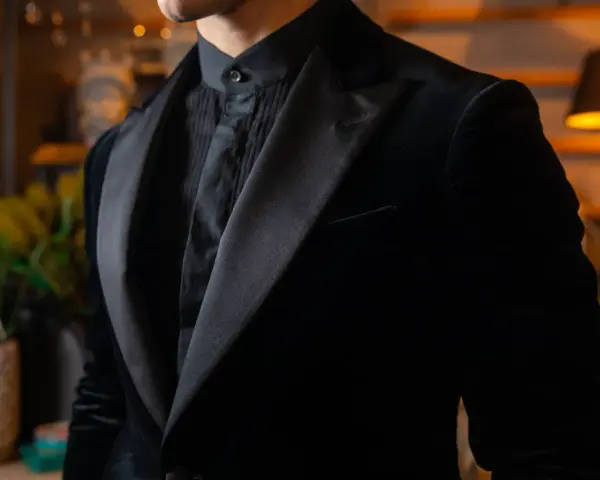Uomo con abito nero in velluto, camicia con jabot e cravatta. Eleganza senza tempo per un abbinamento perfetto.