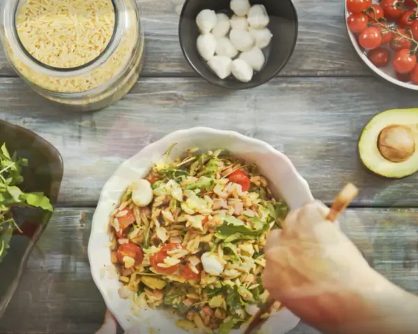 Przygotowanie pysznej sałatki z makaronem orzo z pomidorkami, mozzarellą i rukolą.