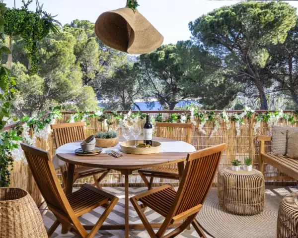 Encantadora decoracion terrazas con mesa de madera, sillas, banco y mucha vegetación. Un oasis verde para disfrutar del aire libre.