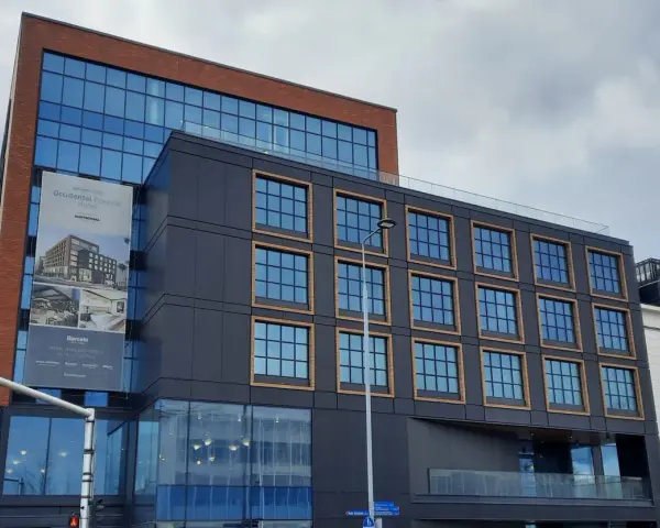 Nowoczesny budynek z cegły i ciemnej fasady, z banerem zapowiadającym otwarcie Occidental Powisle Hotel, części sieci Barceló.
