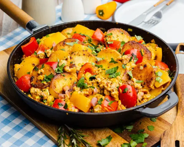 Herzhafte bauernpfanne mit kartoffeln und ei, garniert mit frischer Petersilie und bunten Paprikastücken. Ein deftiges Gericht direkt aus der Pfanne.