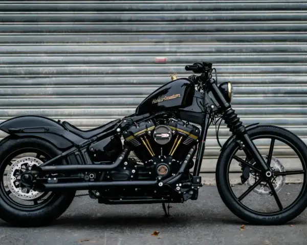 Czarny, klasyczny motocykl Harley-Davidson z błyszczącym lakierem i złotymi akcentami na silniku, gotowy na drogę.
