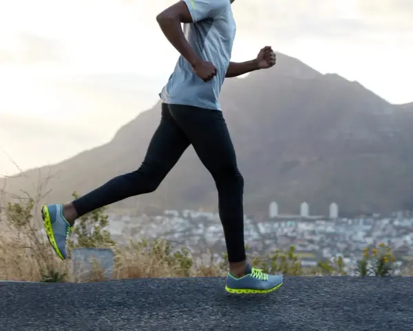 Un homme court sur une route, profitant d'un exercice cardio avec une vue sur la ville et les montagnes.