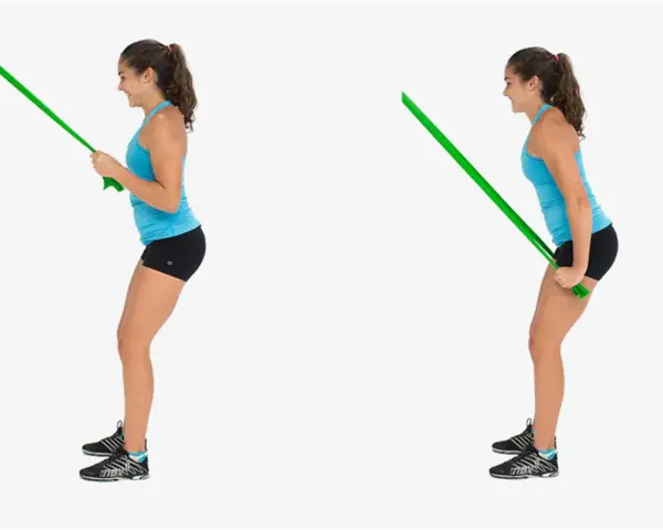 Kvinnlig atlet utför triceps pushdown med ett grönt träningsband.