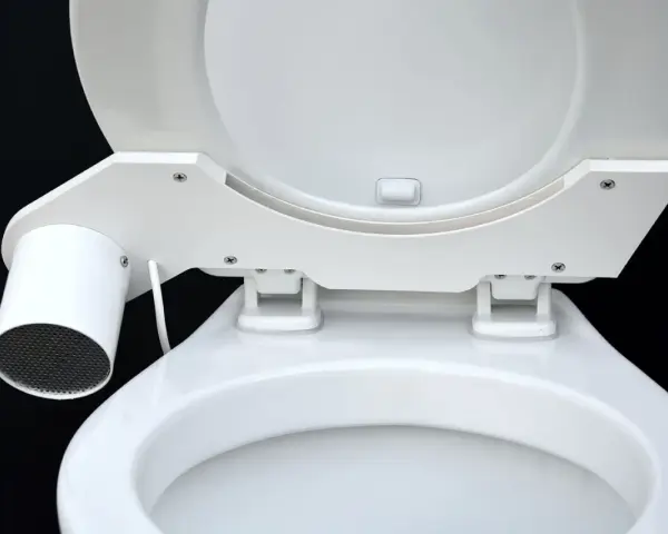 En vit toalett med en innovativ SOG-lösning. En liten cylinder med galler sitter monterad på sidan av sitsen.