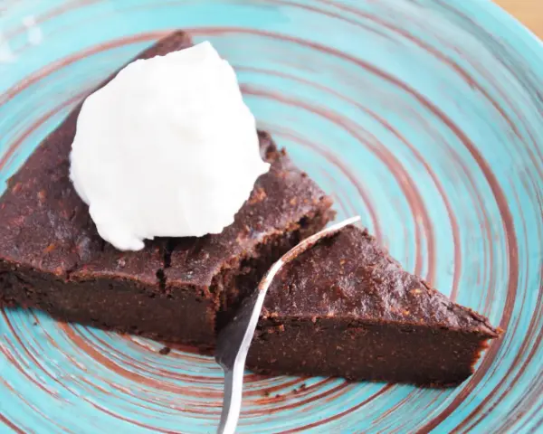 Pyszne keto brownie z cukinii, podane z bitą śmietaną na turkusowym talerzu. Idealne na deser bez wyrzutów sumienia.