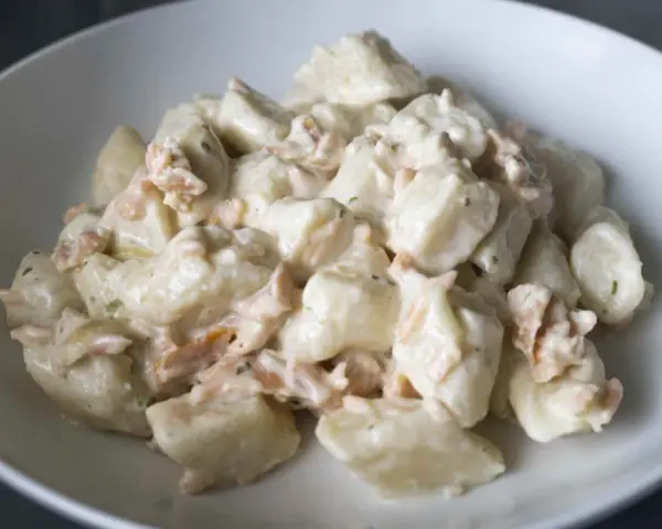 Gnocchi ziemniaczane kontra gnocchi z ricotty w kremowym sosie z łososiem. Pyszne danie w białej misce.