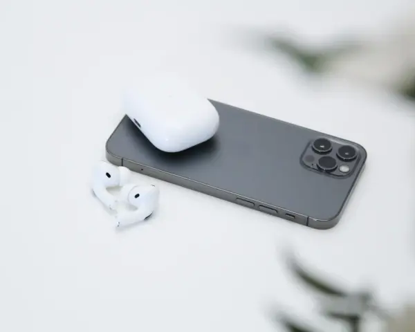 AirPods und Ladecase liegen neben einem Smartphone.