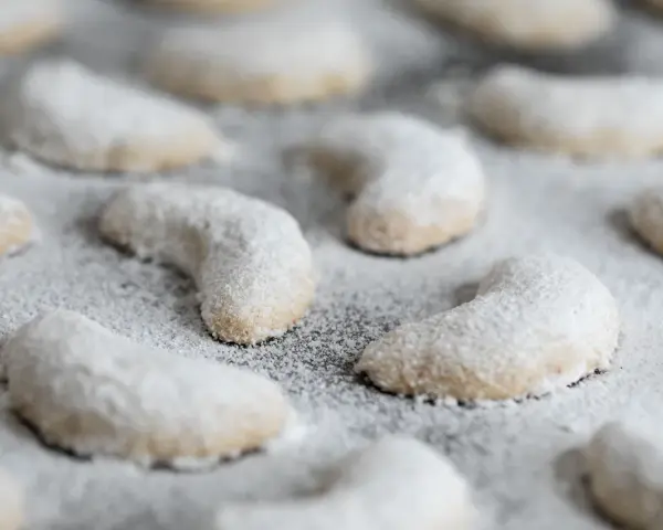 Zarte Vanillekipferl, mit Puderzucker bestäubt, warten darauf, genossen zu werden.