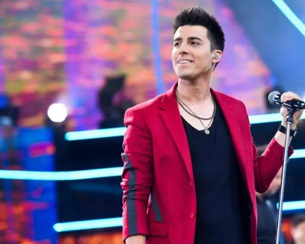 Filip śpiewa na scenie w czerwonej marynarce. Lato i jego żona pewnie są na widowni.