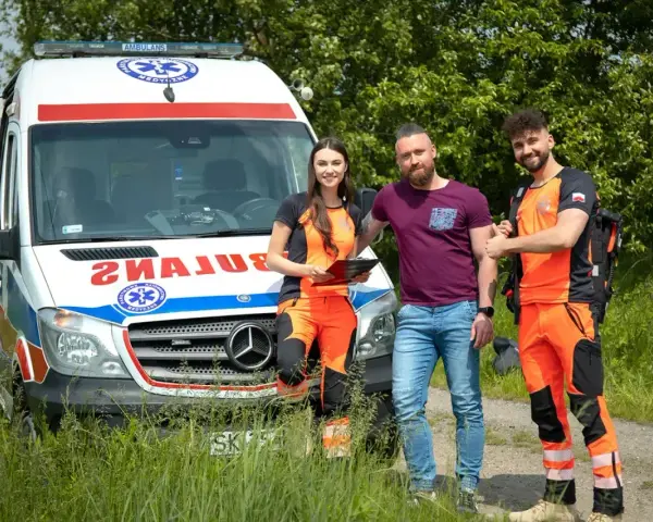 Trzech ratowników medycznych stoi obok karetki. Zastanawiasz się, ile godzin pracuje ratownik medyczny?