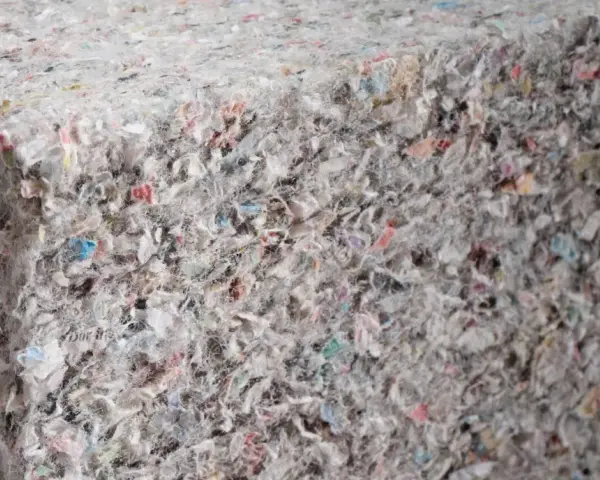 Materiały budowlane: celuloza ocieplenie z recyklingu, tworzące zwartą, włóknistą strukturę z kolorowymi fragmentami.