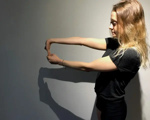 Jeune femme faisant un étirement du poignet, geste clé pour la rééducation de l'épitrochléite et réduire le temps de guérison.