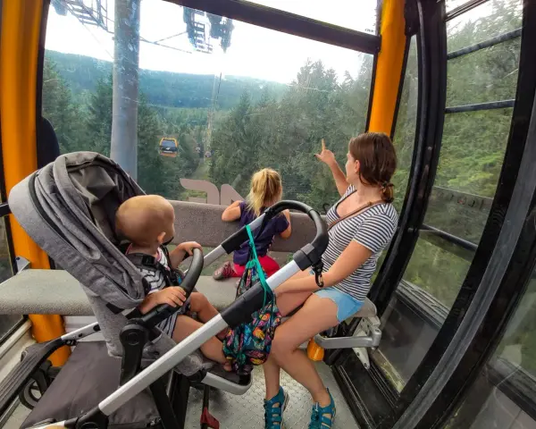 Rodzina w kolejce gondolowej w Górach Izerskich, Świeradów-Zdrój. Dzieci zachwycone widokiem lasu i innych wagoników.
