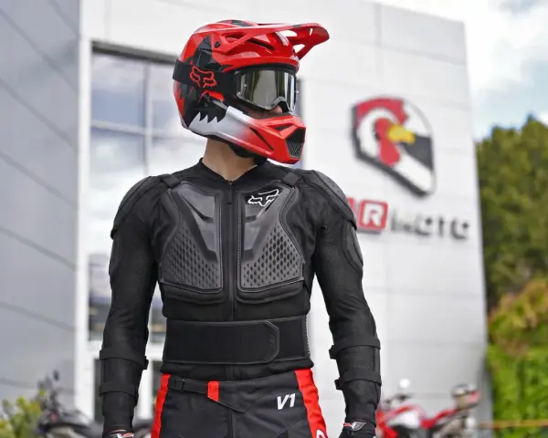 Motocyklista w kasku i ochraniaczach. Kurtka z membraną chroni przed wiatrem i deszczem, zapewniając komfort.