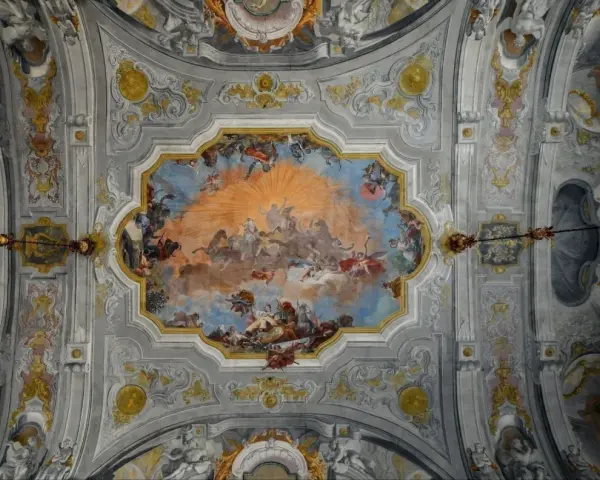 Plafond orné de fresques célestes, un exemple de style **rococo def.**, avec des anges, des chevaux et un soleil éclatant.