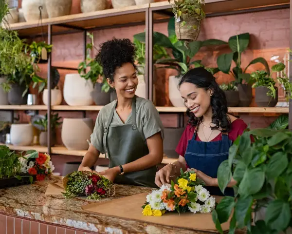 Deux fleuristes souriantes créent des bouquets. Un métier artistique bien payé qui embellit le quotidien.