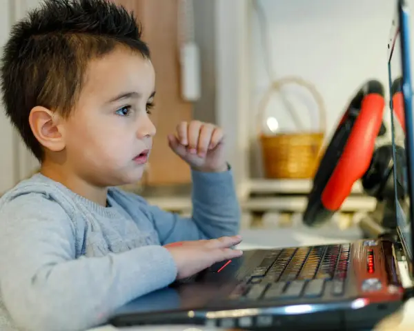 Chłopiec z zaciekawieniem ogląda na laptopie materiały o biologii dla dzieci.
