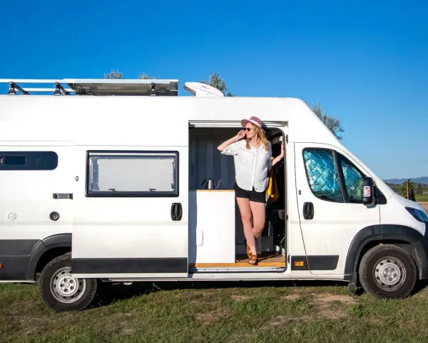 Kobieta w kapeluszu wychodzi z białego kampera Mitsubishi, gotowa na przygodę.