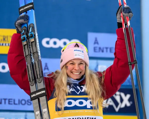 Uśmiechnięta narciarka z nartami w górze, świętuje sukces w biegach narciarskich. Klasyfikacja generalna FIS Cross Country World Cup.