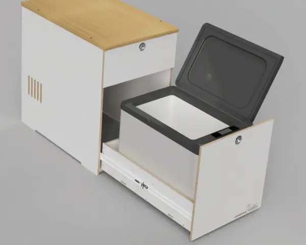 En kylbox med kompressor testas i en vit möbel med trädetaljer. Locket är öppet och lådan är utdragen.