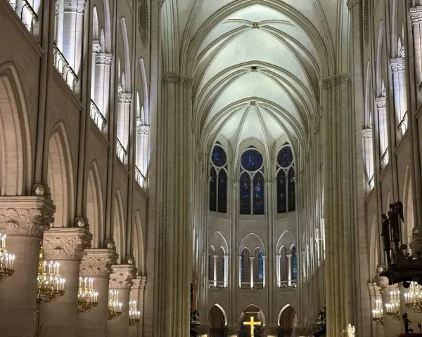 Interior de Notre Dame, con sus impresionantes arcos góticos, vitrales y candelabros dorados. Las **entradas Notre Dame** se abren a este majestuoso espacio.