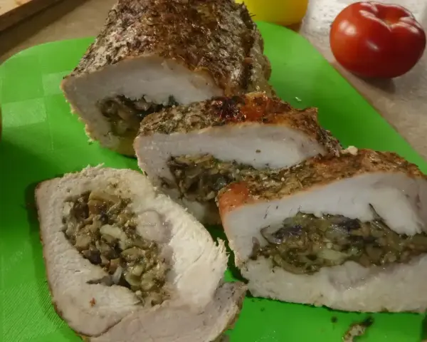 Pyszny kotlet husarski, pieczony z ziołami i nadzieniem grzybowym, pokrojony na desce.