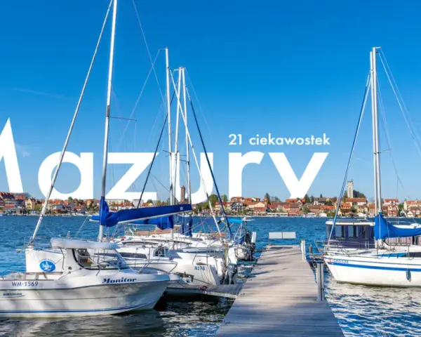Żaglówki cumujące w porcie na Mazurach, Polska. W tle malownicze miasteczko nad jeziorem.