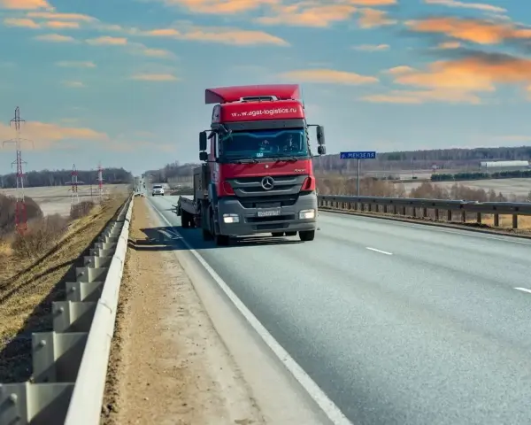 Czerwona ciężarówka jedzie autostradą. Ubezpieczenie kabotażowe zapewnia spokój podczas międzynarodowych transportów.