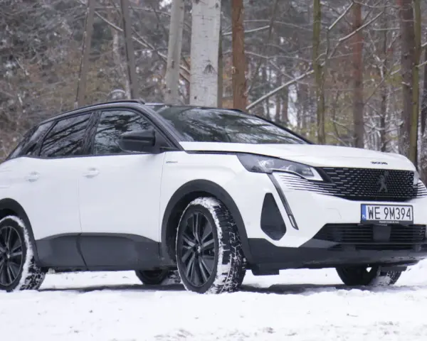 Biały Peugeot 3008 hybryda na śniegu, gotowy na zimowe przygody w lesie.