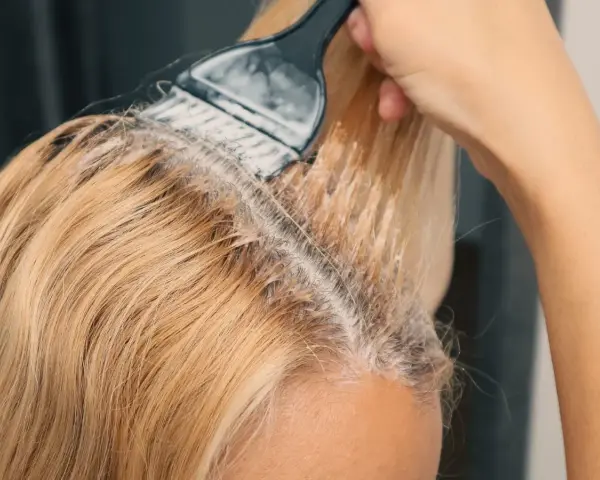 Nakładanie rozjaśniacza na blond włosy, by uzyskać efekt jak naturalnie rozjaśnić włosy.