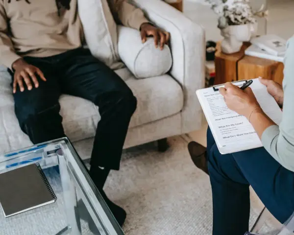 Terapia z psychologiem, który notuje objawy schizofrenii. Pacjent siedzi na kanapie, terapeuta na krześle.
