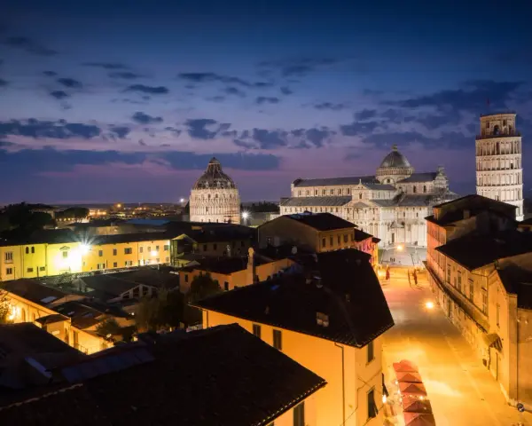 Magnifique paysage de Pise au crépuscule, avec la cathédrale, le baptistère et la tour penchée illuminés. Une belle photographie de paysage.