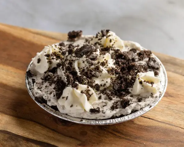 Pyszna masa oreo do tortu, udekorowana bitą śmietaną i pokruszonymi ciasteczkami. Idealna na deser!