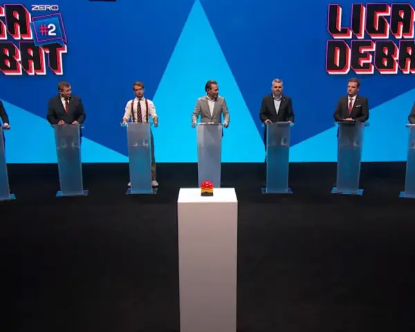 Siedmiu mężczyzn w garniturach stoi za mównicami. W tle logo "Liga Debat #2".
