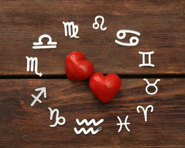 Srebrne symbole znaków zodiaku ułożone w okrąg wokół dwóch czerwonych serc. Wskazują na połączenia znaków zodiaku w miłości.