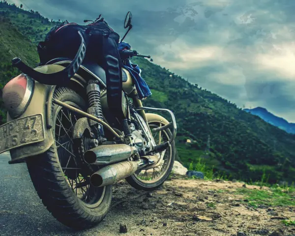 Motocykl gotowy na przygodę, z bagażem na siedzeniu, na tle gór i mapy świata. Marzy o podróży na Atlantic Road w Norwegii.