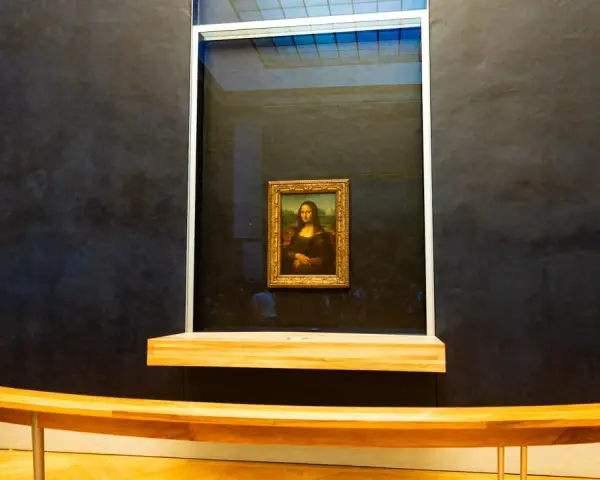 Mona Lisa w muzeum, za pancerną szybą. Słynny obraz Leonarda da Vinci przyciąga tłumy zwiedzających.