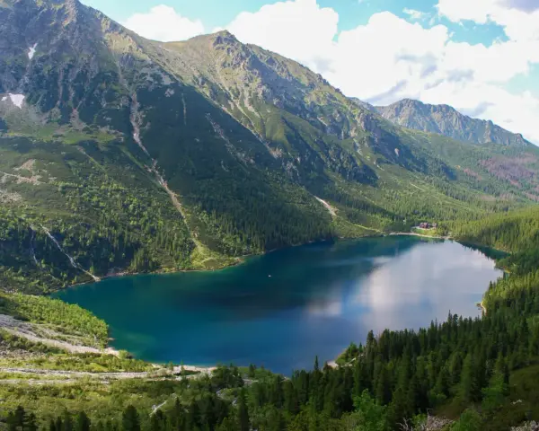 Największe jezioro w Tatrach, Morskie Oko, otoczone zielonymi lasami i skalistymi szczytami.