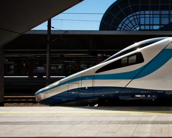 Nowoczesny pociąg PKP Intercity z niebieskimi pasami na tle dworca.