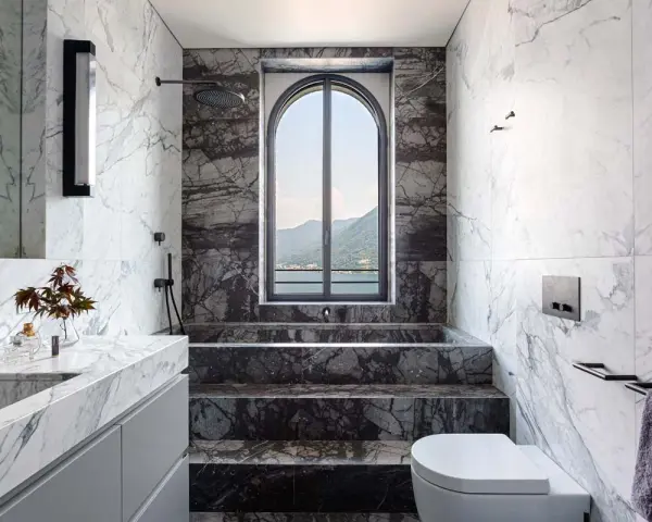 Bagno di lusso con vasca doccia in muratura, rivestimenti in marmo e vista panoramica.