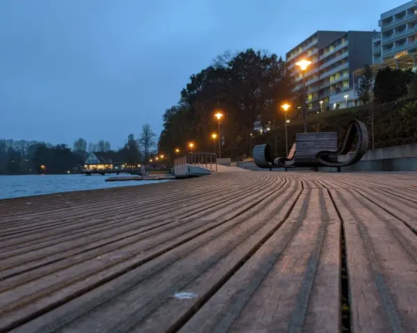 Holzdeck am See mit modernen Bänken und Beleuchtung. Ein schöner Ort für **Bad Segeberg Unternehmungen** am Abend.
