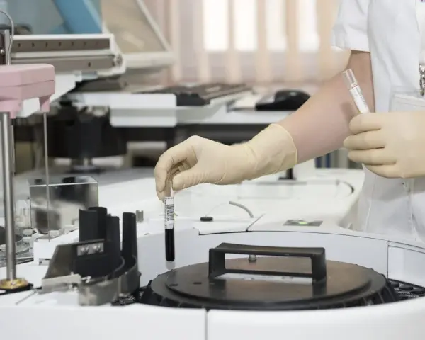 Pracownik w rękawiczkach umieszcza próbkę w automacie analitycznym w laboratoriach Brunel B Co.