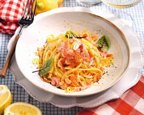 Spaghetti con sughi in bianco, conditi con limone, mandorle e un tocco di rosa.