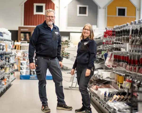 Två anställda står i en butik med färg och verktyg. De hjälper dig gärna att välja rätt färg för att måla fasad.