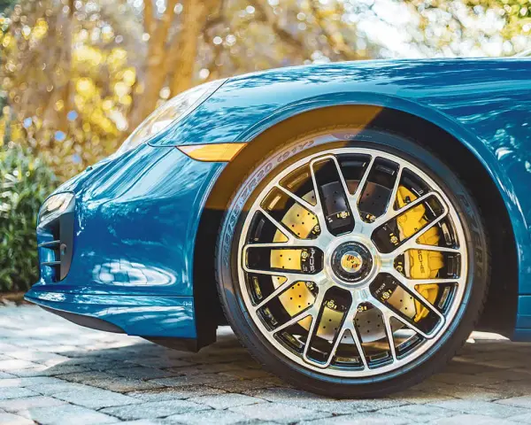 Błękitne Porsche z żółtymi zaciskami hamulcowymi i wieloramiennymi felgami. To jest et felgi, które dodają sportowego charakteru.