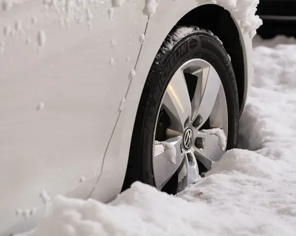 Białe auto w śniegu, widoczna felga z logo VW. Zastanawiasz się, jak zmierzyć rozstaw śrub?